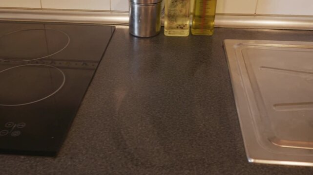 Pan across a modern kitchen countertop, induction hob, and sink