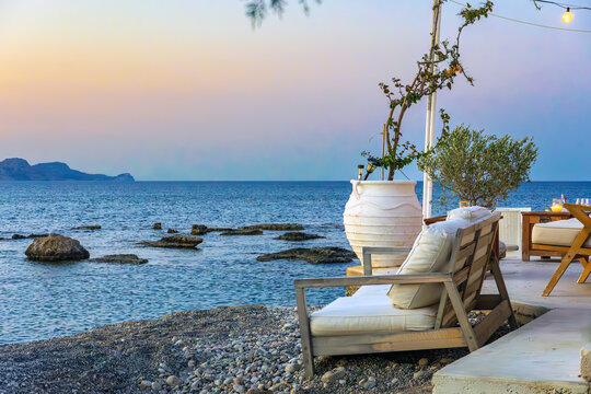 Cozy seaside lounge terrace with comfortable seating with traditional amphora pot overlooking the Mediterranean Sea at sunset in Kolymbia Rhodes