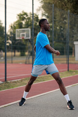 Fototapeta premium African american athlete stretching outdoors on sports court