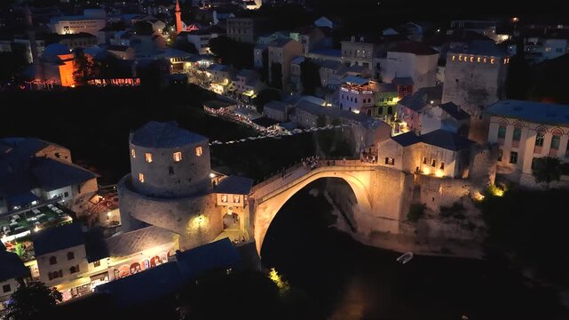 Mostar, Bosnia and Herzegovina - June 7, 2026: High aerial approach toward the illuminated Old Bridge overlooking the Neretva River