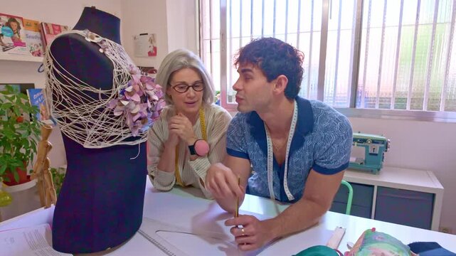 Young fashion designer brainstorming with seamstress in sewing workshop