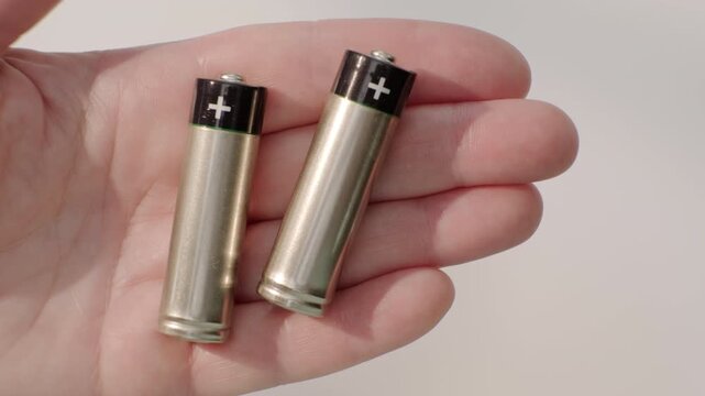 Two cylindrical batteries AA on palm of person's hand close-up, top view