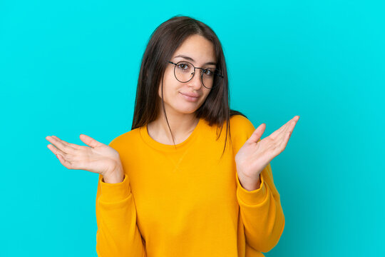 Young Ukrainian woman isolated on blue background With glasses and having doubts