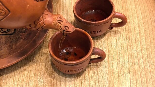 Pouring Hot Java Tea Into Handcrafted Indonesian Clay Teacup. Culture video 4k 60 fps.