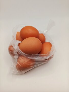 Brown chicken eggs packed inside a transparent plastic bag isolated on a white background. Daily grocery product representing food packaging, shopping, fresh ingredients, and household supplies.