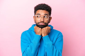 Obraz premium Young Brazilian man isolated on pink background With glasses and tired