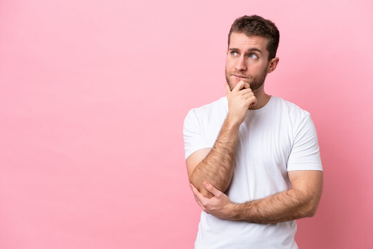 Young caucasian man isolated on pink background having doubts and thinking