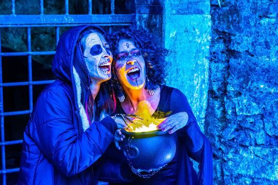 Two women celebrating halloween wearing spooky makeup and witch costumes