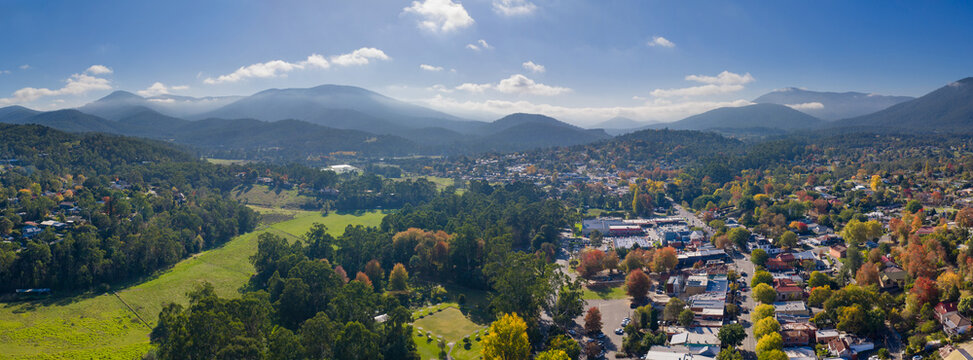 Aerial panorama view of a rural township below mountains with morning fog