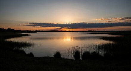 Naklejka premium Serene Twilight Reflecting Golden Hues Across Tranquil Water Body with Reeds in the Foreground Evoking Peaceful Evening Ambiance of Rural Landscape and Nature's Gentle Embrace.