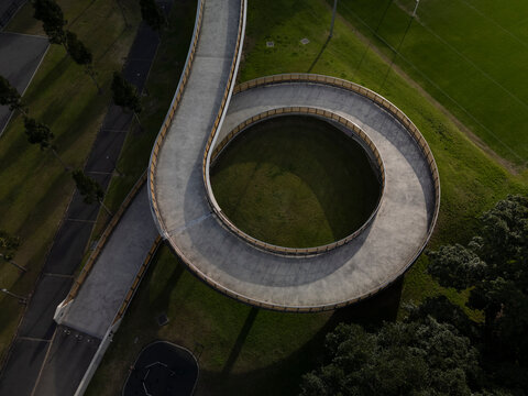 Large spiral bridge aerial view carrying pedestrians, cyclists and joggers. Bridge in beautiful afternoon light