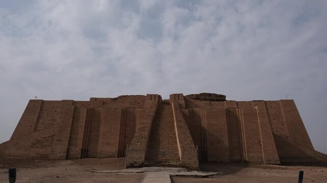 Ancient Sumerian ziggurat mudbrick staircase rises steeply against cloudy sky