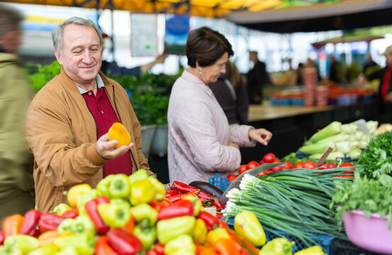 Aged man and woman customers buying pepper in open-air market