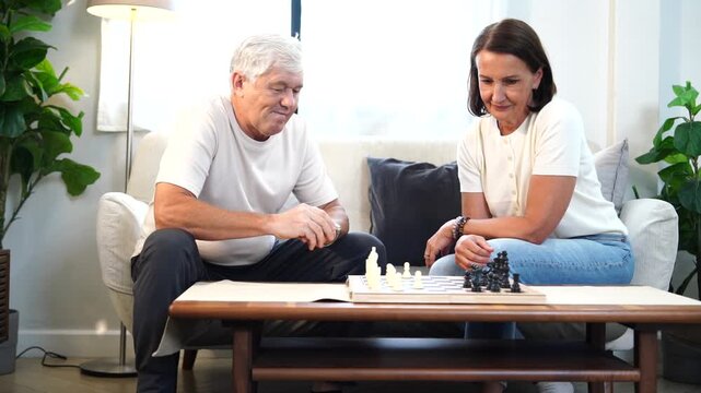 The elderly family, including the grandparents, were relaxing, playing chess together, and chatting in the living room of their house. 