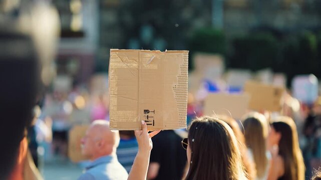 People hold signs during a march in a busy city square in the afternoon