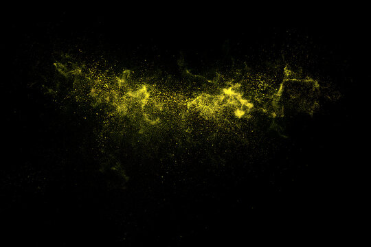 Yellow powder explosion against a black background a dynamic particle spray effect