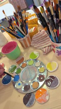 Artist dipping paintbrush into ceramic palette. Creative art master class process in cozy workshop