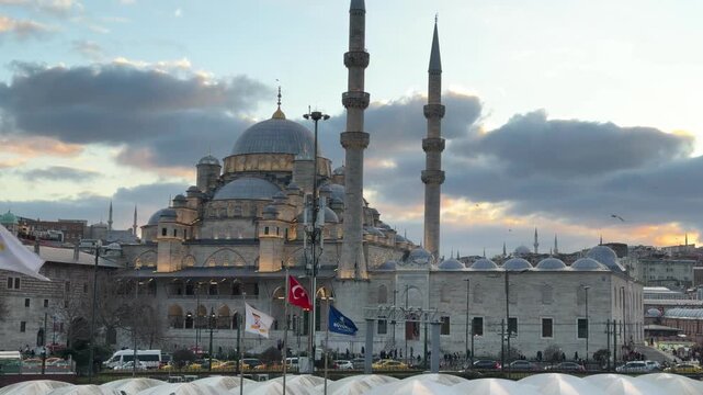 Wide angle landscape view capturing the historic Yeni Cami mosque architecture with its monumental domes and towering minarets at sunset in Istanbul, Turkey.