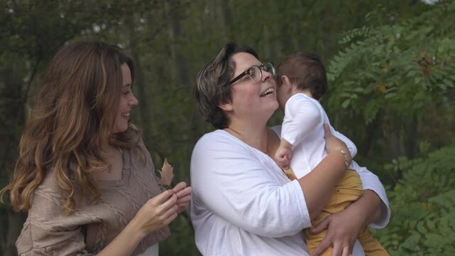 Lesbian couple playing with their son and autumn leaves