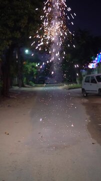 A flying helicopter firework spins and emits bright sparks on a quiet residential street during Diwali celebrations, creating a festive nighttime scene on the eve of Diwali showing celebrations
