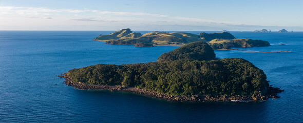 Obraz premium A panoramic view of the islands and coastline of Slipper Island, Coromandel Peninsula,, New Zealand, under a clear sky. The deep blue ocean surrounds the lush green islands
