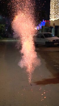 A bomb sparkler firework emits bright sparks on a quiet residential street during Diwali celebrations, creating a festive nighttime scene on the eve of Diwali showing celebrations