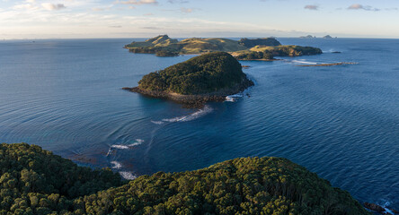 Obraz premium A panoramic view of the islands and coastline of Slipper Island, Coromandel Peninsula,, New Zealand, under a clear sky. The deep blue ocean surrounds the lush green islands