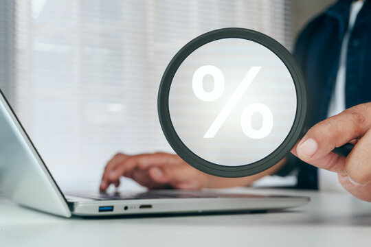Business professional using magnifying glass with percentage symbol to analyze interest rates, tax planning, discount pricing, loan comparison, financial audit, investment return, finance strategy
