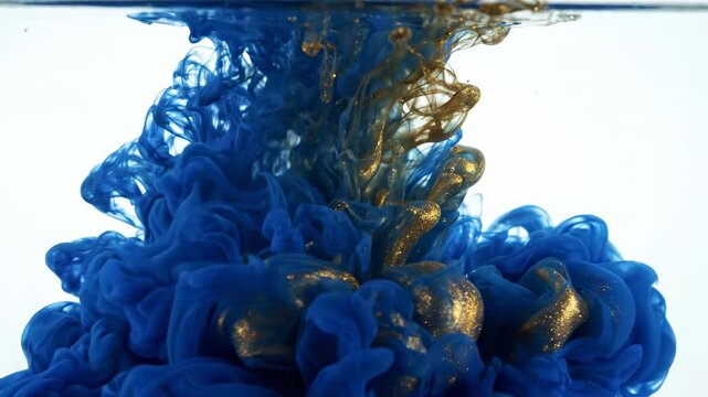 Abstract swirling blue and gold ink clouds dissolving in water, forming ethereal smoke like patterns, fluid motion, mesmerizing effects