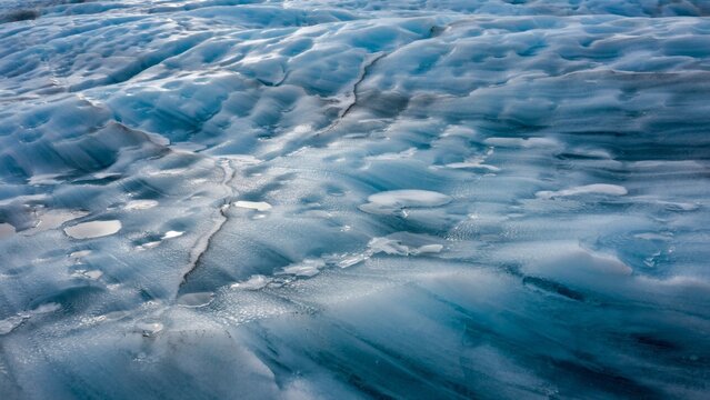 Close-up macro view of blue glacial ice with intricate textures and cracks in polar region