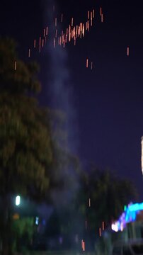A flying helicopter firework spins and emits bright sparks on a quiet residential street during Diwali celebrations, creating a festive nighttime scene on the eve of Diwali showing celebrations