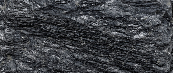 Naklejka premium Black stone texture showing a close up of a rough natural slate rock wall surface with detailed wavy organic layers offers a premium dark backdrop for design layouts