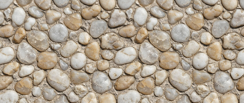 Pebble stones arranged closely together forming a smooth natural mosaic surface with soft cream and grey rounded stone tones