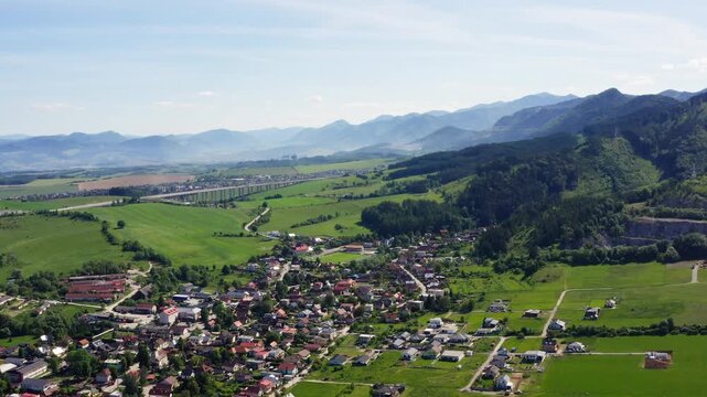4K aerial view of Turie village in Zilina region, Slovakia. Beautiful panoramic shot of countryside houses, green fields, and the D1 highway bridge with Mala Fatra mountains background