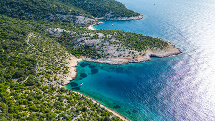 Aerial view of the stunning Adriatic coastline on Cres Island, Croatia. Crystal-clear turquoise waters meet lush green Mediterranean vegetation under bright summer sun, inviting exploration. Beach Gra © Viktor