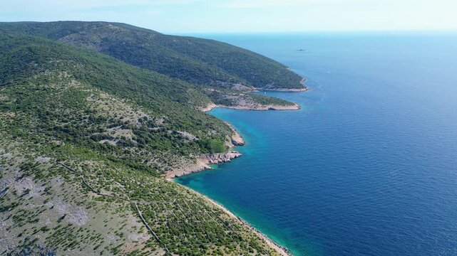 Breathtaking aerial view of Croatia's Adriatic coast. Lush green hills meet crystal-clear turquoise waters, revealing hidden coves and distant sailboats under a summer sky. Beach Grabrovica
