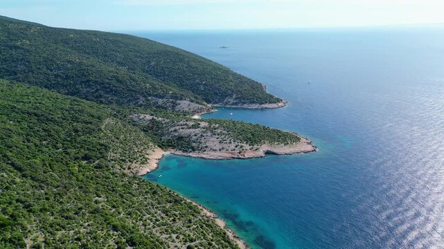 Breathtaking aerial view of Croatia's Adriatic coast. Lush green hills meet crystal-clear turquoise waters, revealing hidden coves and distant sailboats under a summer sky. Beach Grabrovica