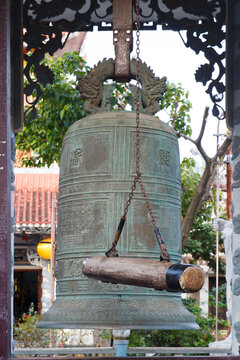 A close-up of bronze bell with wooden log-striker for ringing at Chua Tan Thai Pagoda at Danang, Vietnam