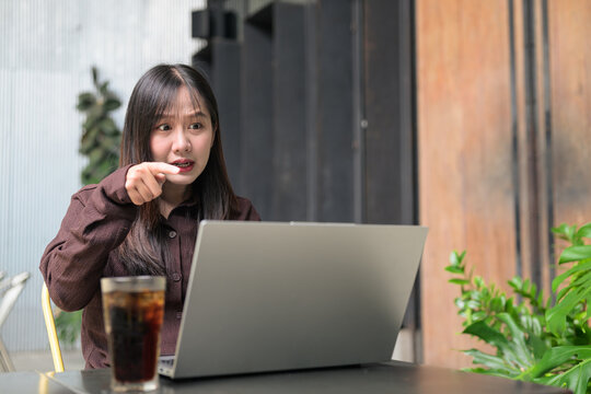 Frustrated Asian Woman Pointing Accusingly at Her Laptop Screen