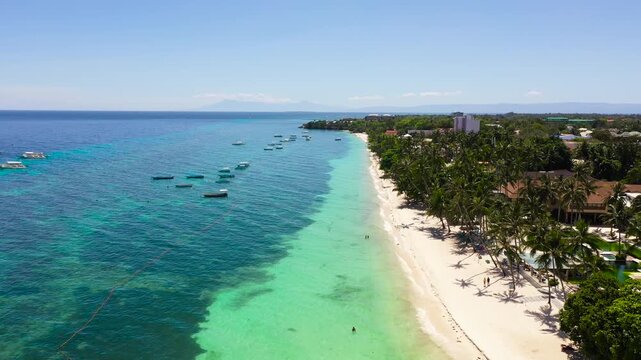 Sandy beach and azure water surrounded by a coral reef. Panglao, Alona beach, Philippines. Summer and travel vacation concept.