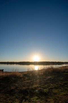 Golden sun glows over calm lake surface