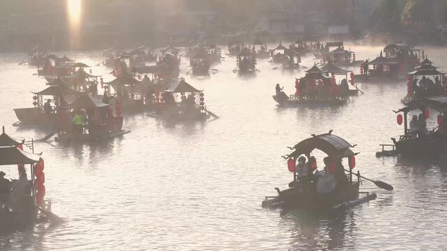 Rak Thai Village, Mae Hong Son, Thailand - November 25, 2025: Traditional Chinese-style boats sail on a misty lake during a beautiful winter at Ban Rak Thai village. Famous travel destination.