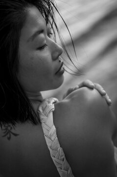 Close-up portrait of a beautiful Asian woman by the sea with glowing tanned skin. Natural skincare, self care and wellness concept, aesthetic summer beauty, healthy complexion and coastal lifestyle