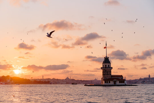 Maiden&rsquo;s Tower at sunset with seagulls over the Bosphorus and warm pastel sky above Istanbul, Turkey.