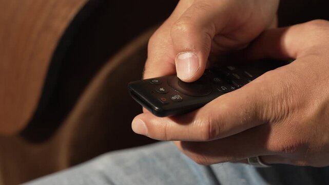 Close up of man hands using smart TV remote control at home