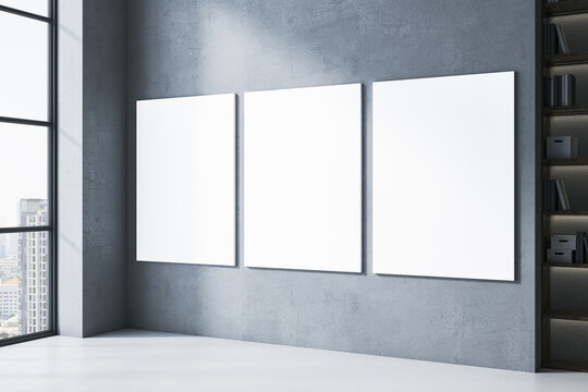 Triptych of blank white canvases mockup on gray concrete wall in modern room with panoramic city view window and dark bookshelf. 3D Rendering