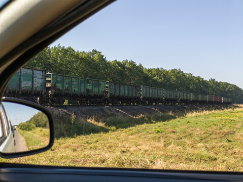 View from car side mirror showing long freight train