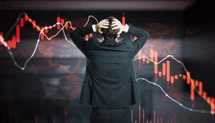Stressed businessman holding head in hands facing screen with red falling candlestick charts and numbers, stock market crash and trader panic concept. © Who is Danny
