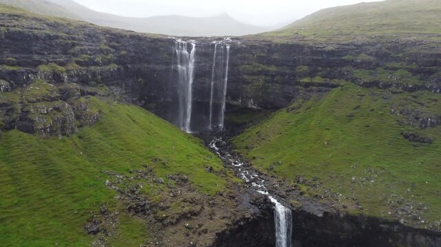 Fossa waterfall in moody weather with misty fog and light rain, Faroe Islands.