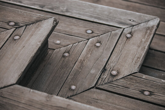 Close-up view of wooden deck boards arranged in a herringbone pattern with visible nails and weathered texture, showcasing craftsmanship and natural materials